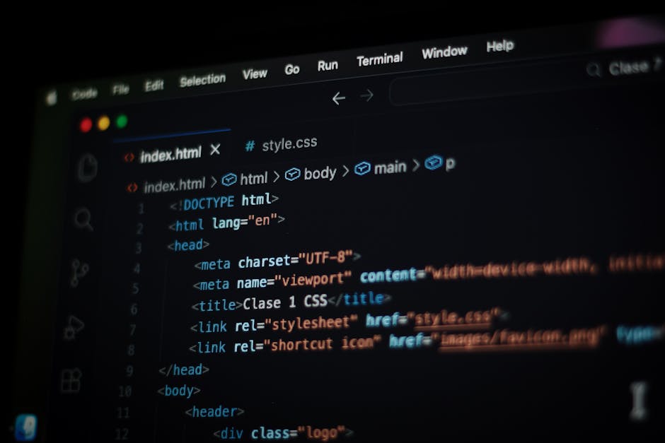 Close-up of a person's hands typing on a MacBook with a dark-themed coding editor open on the screen, displaying lines of green, blue, and white code. The laptop is placed on a black surface, and the 